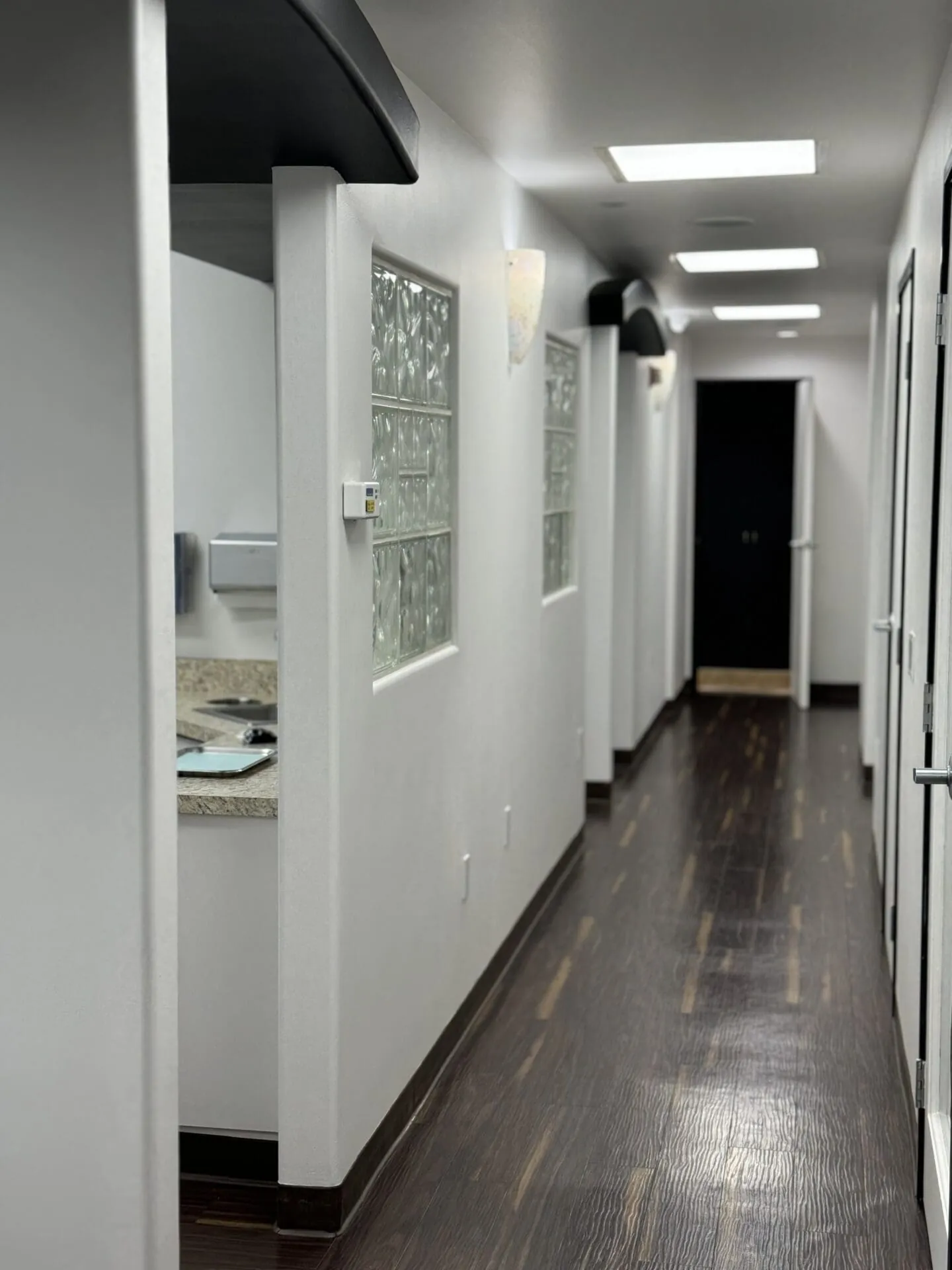 White hallway with dark wood floor.